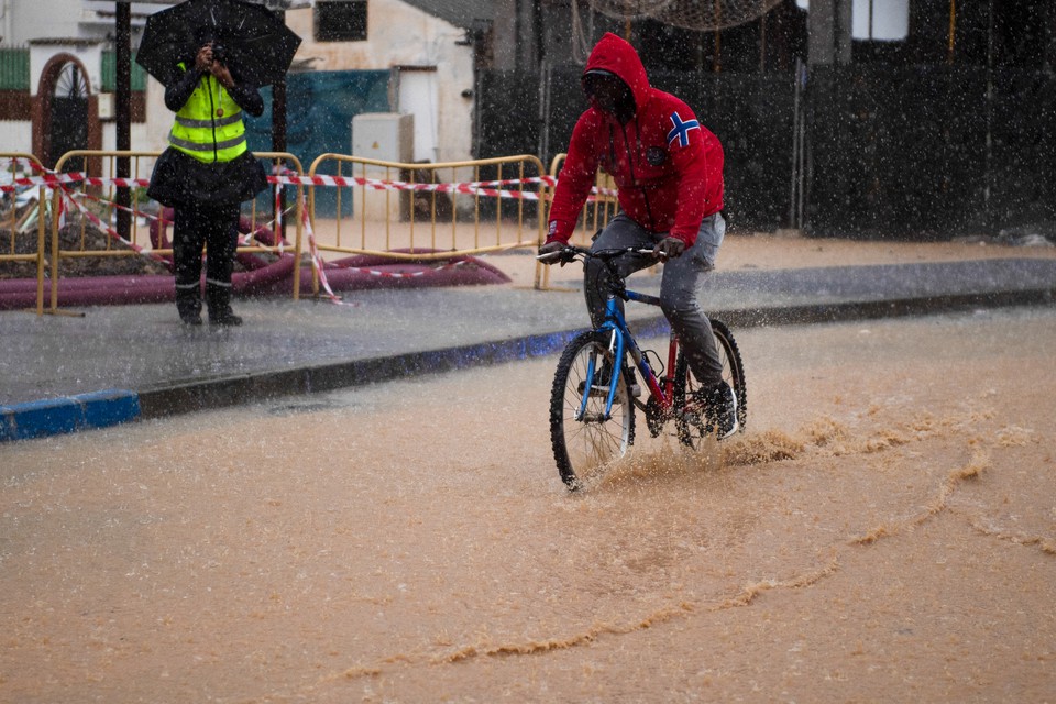 Homem anda de bicicleta por uma rua inundada em Campanillas, perto de Mlaga, sul da Espanha (Foto: JORGE GUERRERO / AFP)