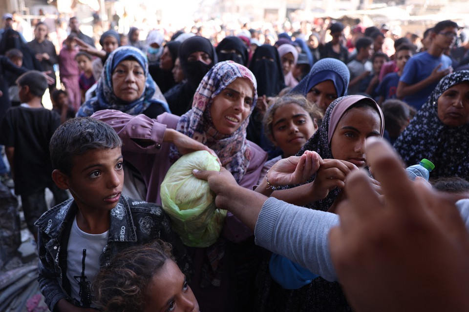 Palestinos esperam em fila para receber po em frente a uma padaria em Khan Yunis, no sul da Faixa de Gaza (Foto: BASHAR TALEB / AFP
)