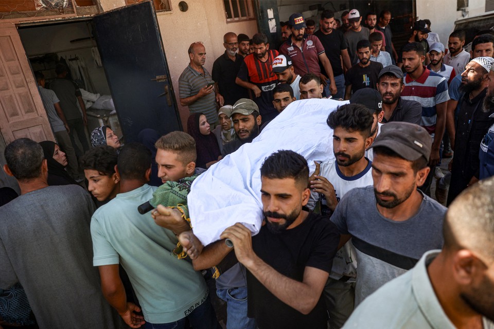 Pessoas em luto carregam o corpo de um homem que foi morto pelo bombardeio israelense em escola em Nuseirat (Foto: EYAD BABA / AFP
)