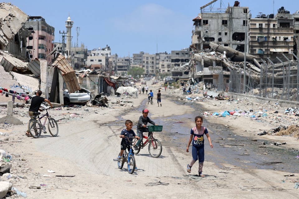 Crianas palestinas andam de bicicleta por uma rua devastada pelo bombardeio israelense na Cidade de Gaza (Foto: AFP)