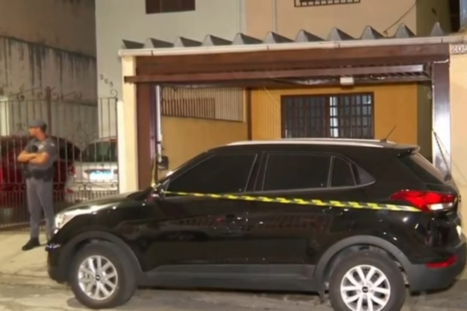 Policiais na frente da casa de adolescente que confessou ter matado a tiros os pais adotivos e a irmã em SP (Crédito: Reprodução / TV Globo)