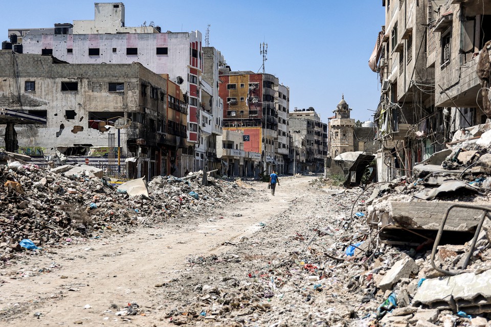 Homem passa por escombros e edifcios danificados ao longo de uma rua no distrito de Tuffah, a leste da Cidade de Gaza (Foto: OMAR AL-QATTAA / AFP
)