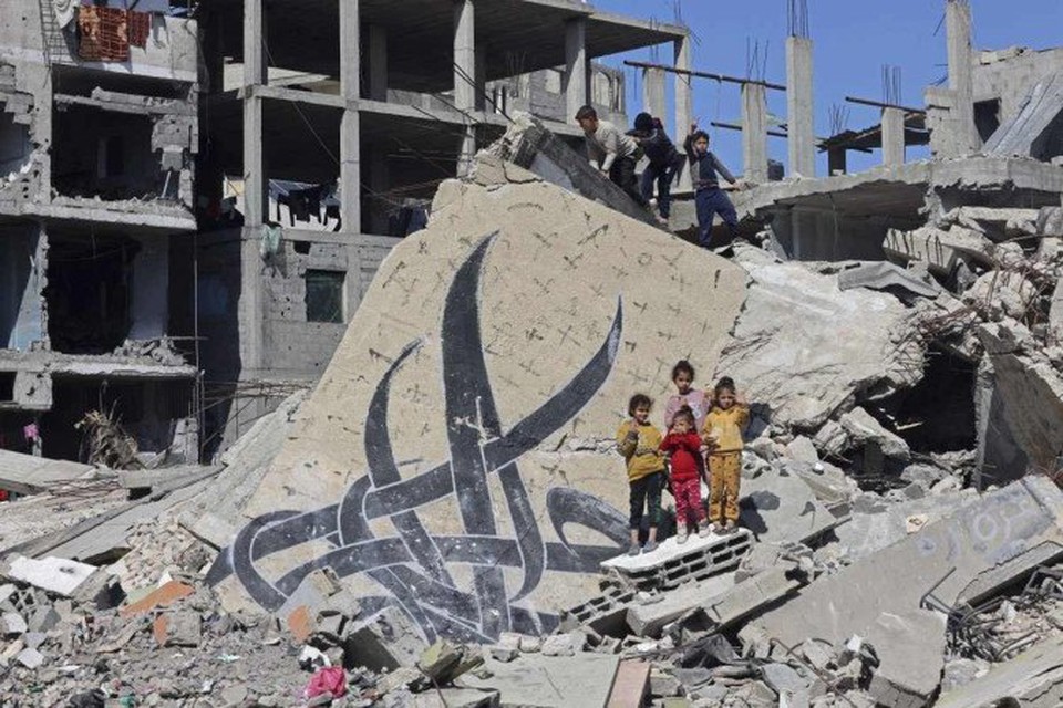 Crianas posam ao lado de um mural que restou em escombros de um edifcio destrudo em Rafah (crdito: MOHAMMED ABED / AFP)