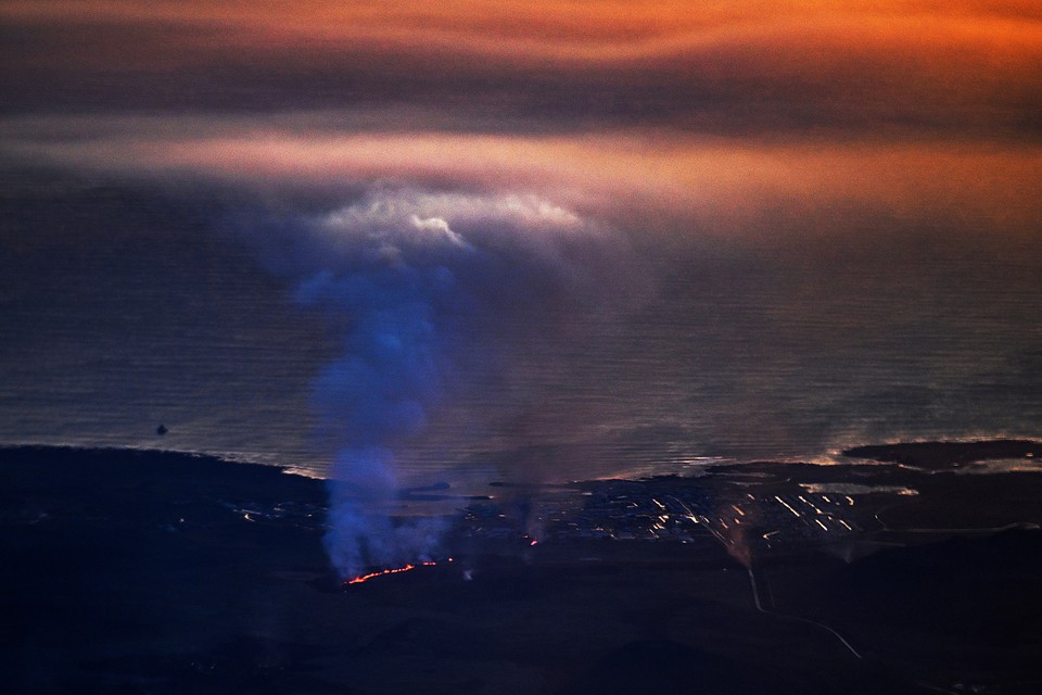 Exploses de lava e fumaa so vistas perto de edifcios residenciais na cidade de Grindavik, no sudoeste da Islndia, aps uma erupo vulcnica em 14 de janeiro de 2024 (Crdito: SERGEI GAPON / AFP)