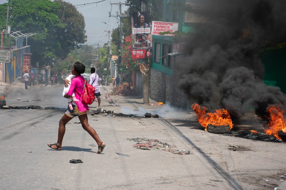 Uma mulher carregando uma criana foge depois que tiros foram ouvidos em Porto Prncipe, Haiti, nesta quarta-feira (20) (Foto: CLARENS SIFFROY / AFP
)
