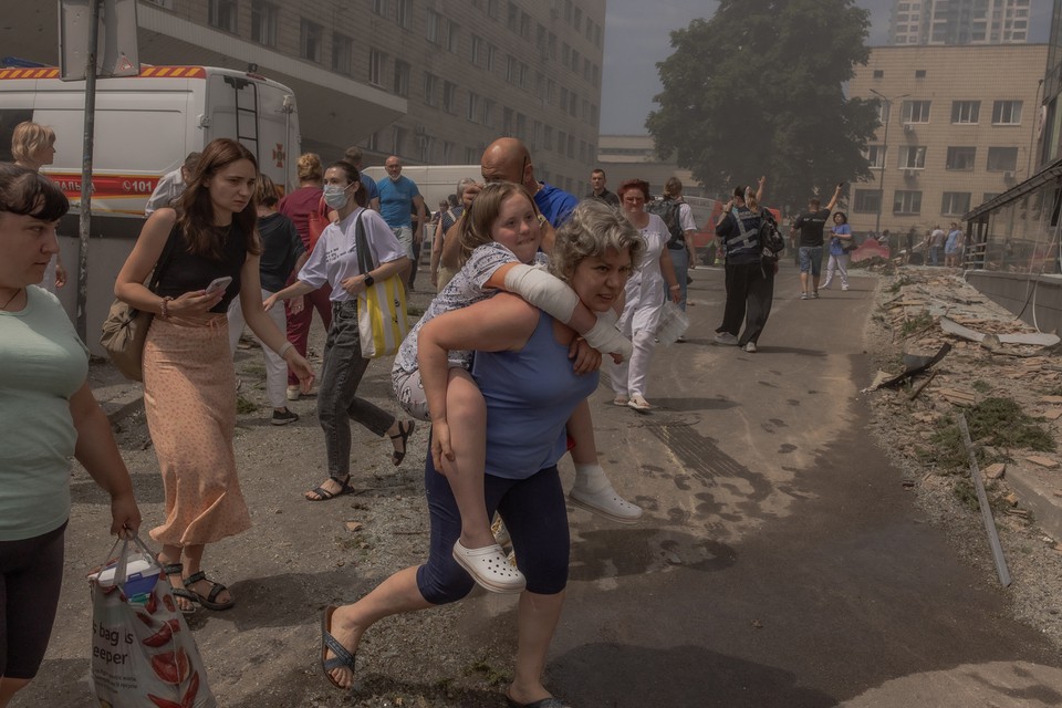 Mulher carrega menina ao lado de prdio fortemente danificado do Hospital Infantil Ohmatdyt aps um ataque com msseis russos na capital ucraniana, Kiev (Foto: ROMAN PILIPEY / AFP
)