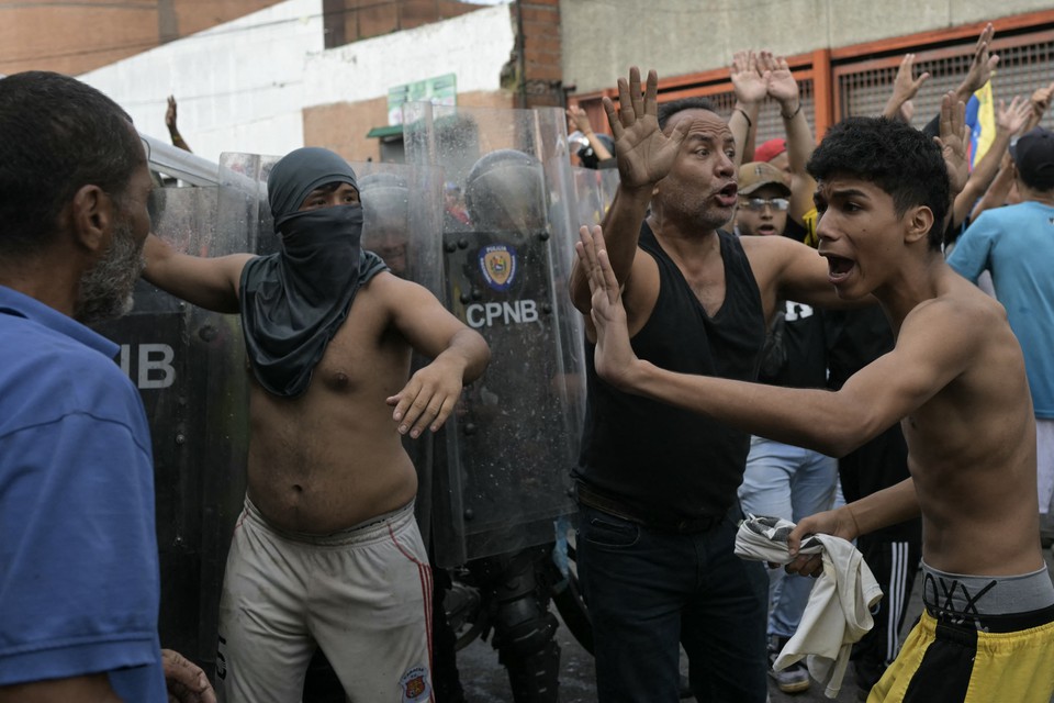 Manifestantes tentam se acalmar entre si enquanto entram em confronto com policiais durante um protesto contra o governo do presidente venezuelano Nicols Maduro em Caracas (Foto: YURI CORTEZ / AFP
)