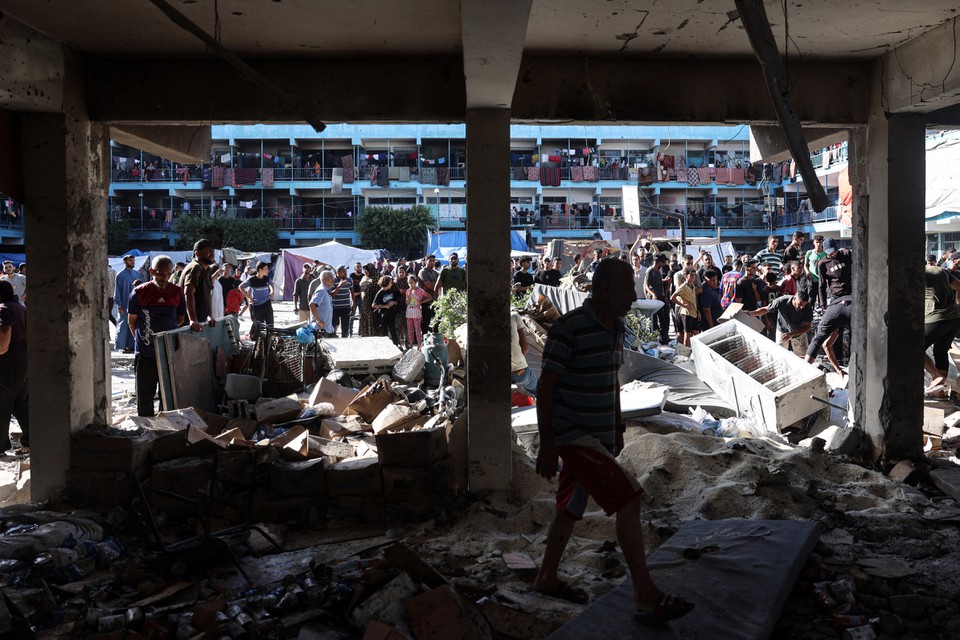 Palestinos verificam o terreno de uma escola depois que um ataque areo israelense atingiu o local, em Nuseirat, no centro da Faixa de Gaza (Foto: EYAD BABA / AFP
)