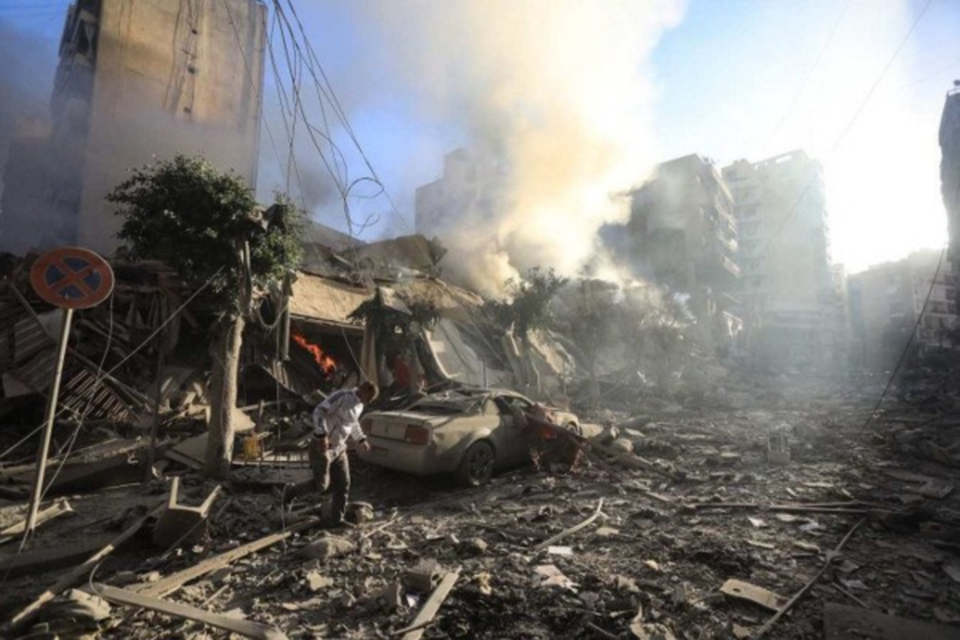 Morador de Beirute caminha sobre escombros de prdio destrudo durante ataque areo israelense, no bairro de Moawwad (sul)  (Crdito: AFP)