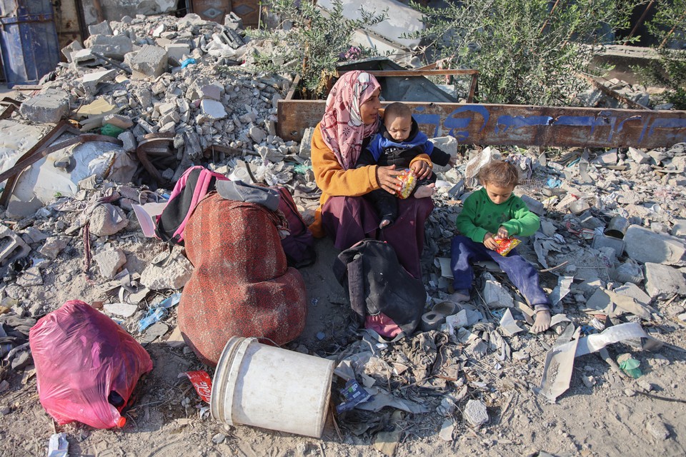 Mulher descansa com seus filhos enquanto palestinos deslocados fogem de Beit Lahia, no norte da Faixa de Gaza (Foto: Omar AL-QATTAA / AFP
)