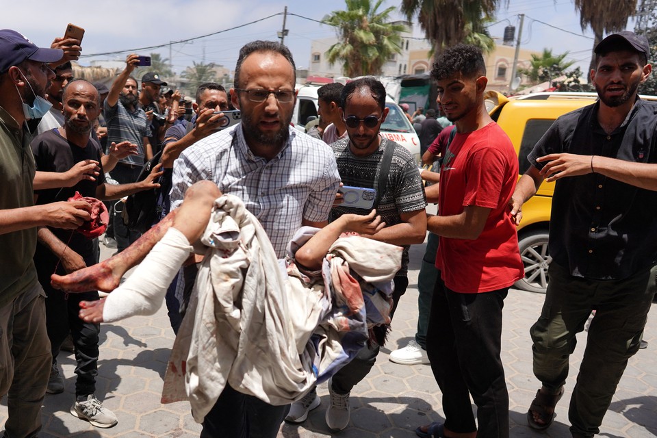 Homem corre carregando uma criana ferida aps o bombardeio israelense contra um apartamento residencial na Faixa de Gaza (Foto: BASHAR TALEB / AFP
)