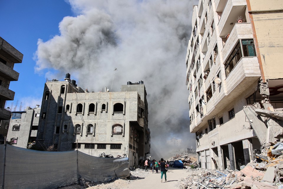 Palestinos observam fumaa subindo de um prdio atingido por um ataque israelense no bairro de Rimal, no centro da cidade de Gaza (Foto: OMAR AL-QATTAA / AFP
)