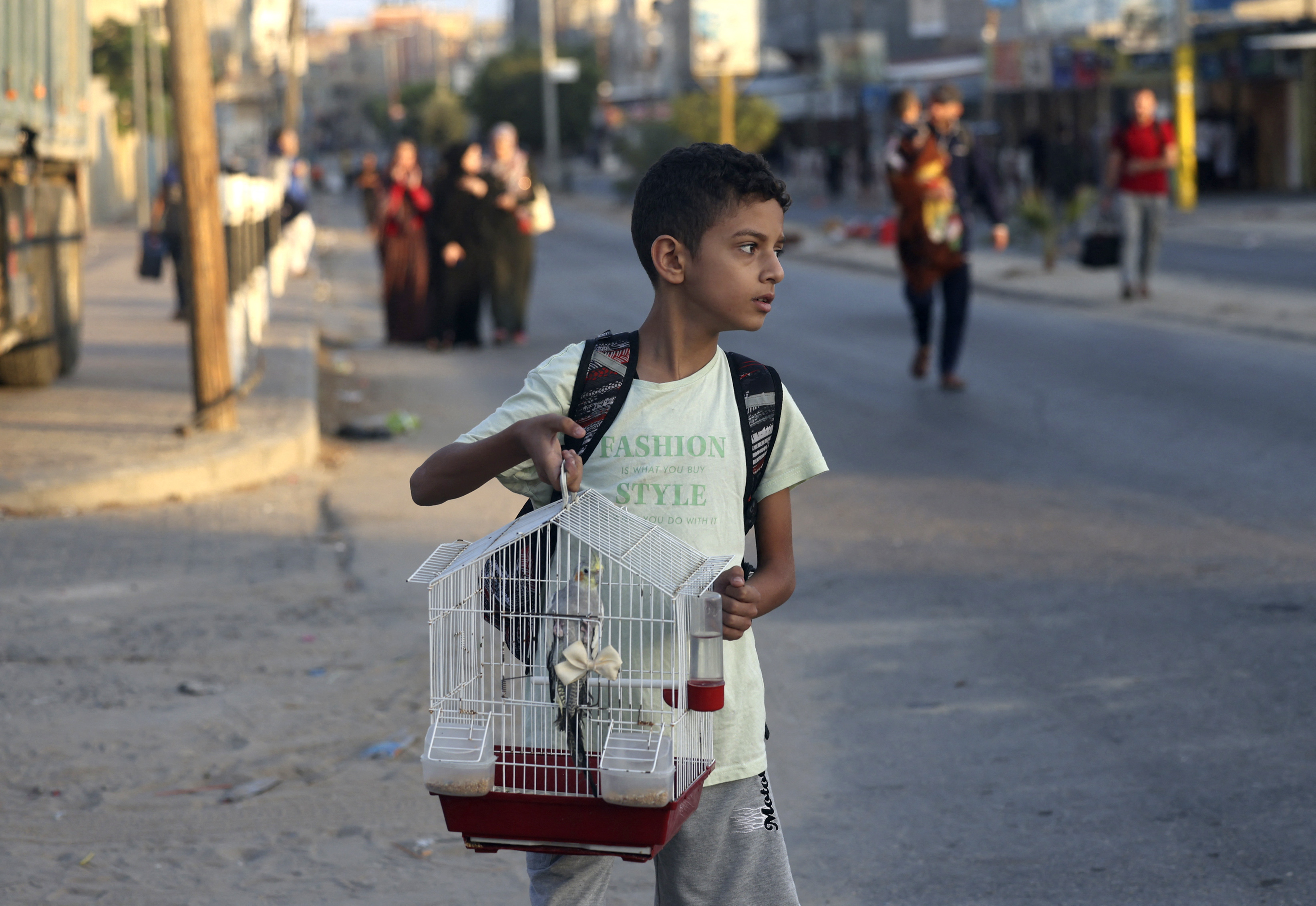 Um menino palestino carrega seu pssaro de estimao em uma gaiola enquanto famlias deixam suas casas aps um ataque israelense (CRDITO: MOHAMMED ABED / AFP)