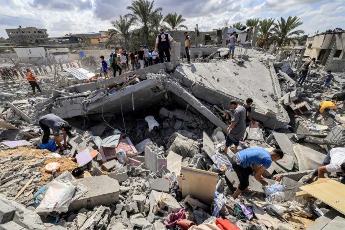 Pessoas inspecionam os restos de um edifcio destrudo aps o bombardeio israelense em Khan Yunis, no sul da Faixa de Gaza, em 18 de outubro de 2023 (crdito: AFP)